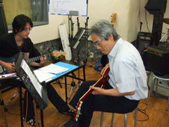 ���Ȑ��k����́A�M�^�[�\�����K�B �搶�̓o�b�L���O�B